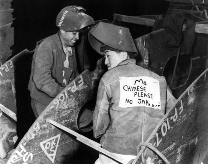 Two workers in welding gear interacting amid a historical photograph depicting a world you'd hardly recognize today.