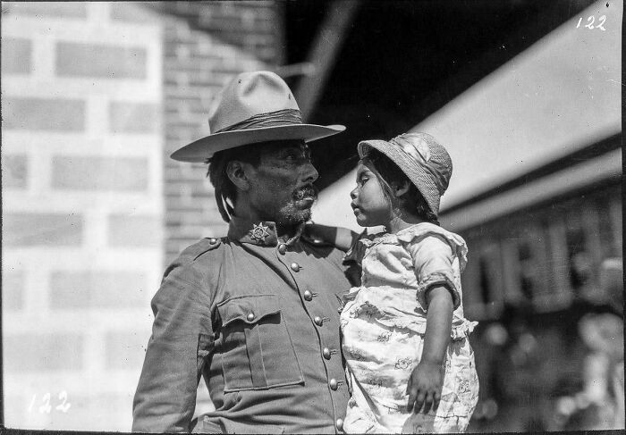 Black and white historical photograph of a man in uniform holding a young girl, depicting a world you'd hardly recognize today.