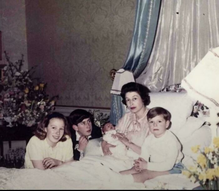 Historical photograph showing a family with mother and children in a vintage bedroom setting from a past world.