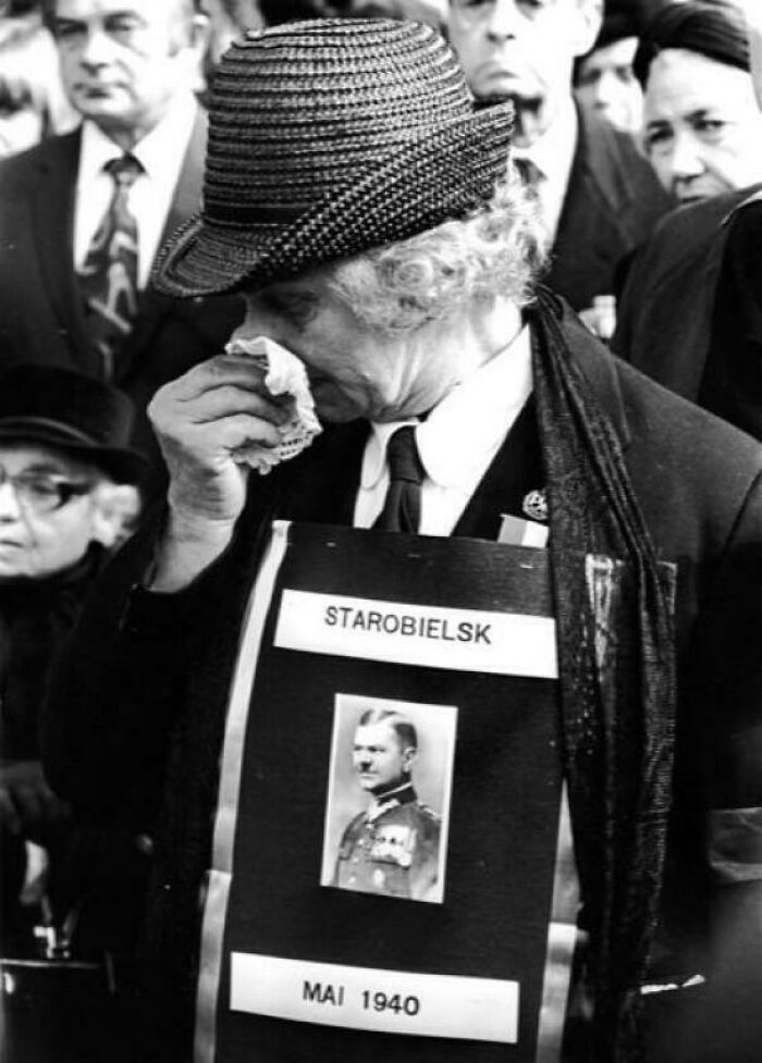 Black and white historical photograph of a grieving woman wearing a sign with Starobielsk and Mai 1940 during a memorial.