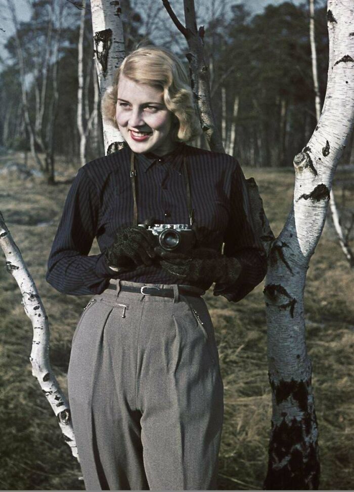 Young woman with vintage camera outdoors among birch trees in an interesting historical photograph depicting a world long gone.