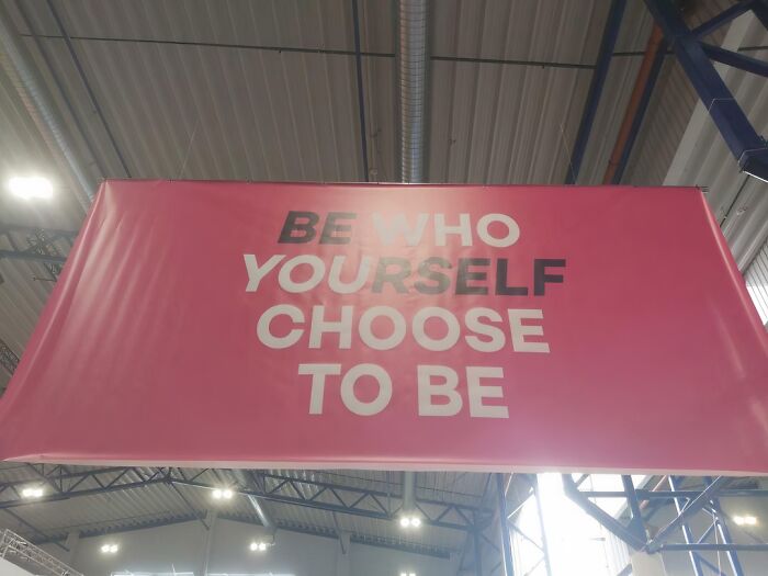 Designer sign with confusing text saying Be Who Yourself Choose To Be hung in an industrial space illustrating design fails.