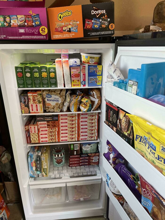 Fridge contents packed with snacks, frozen foods, and beverages, illustrating unconventional fridge organization and storage.