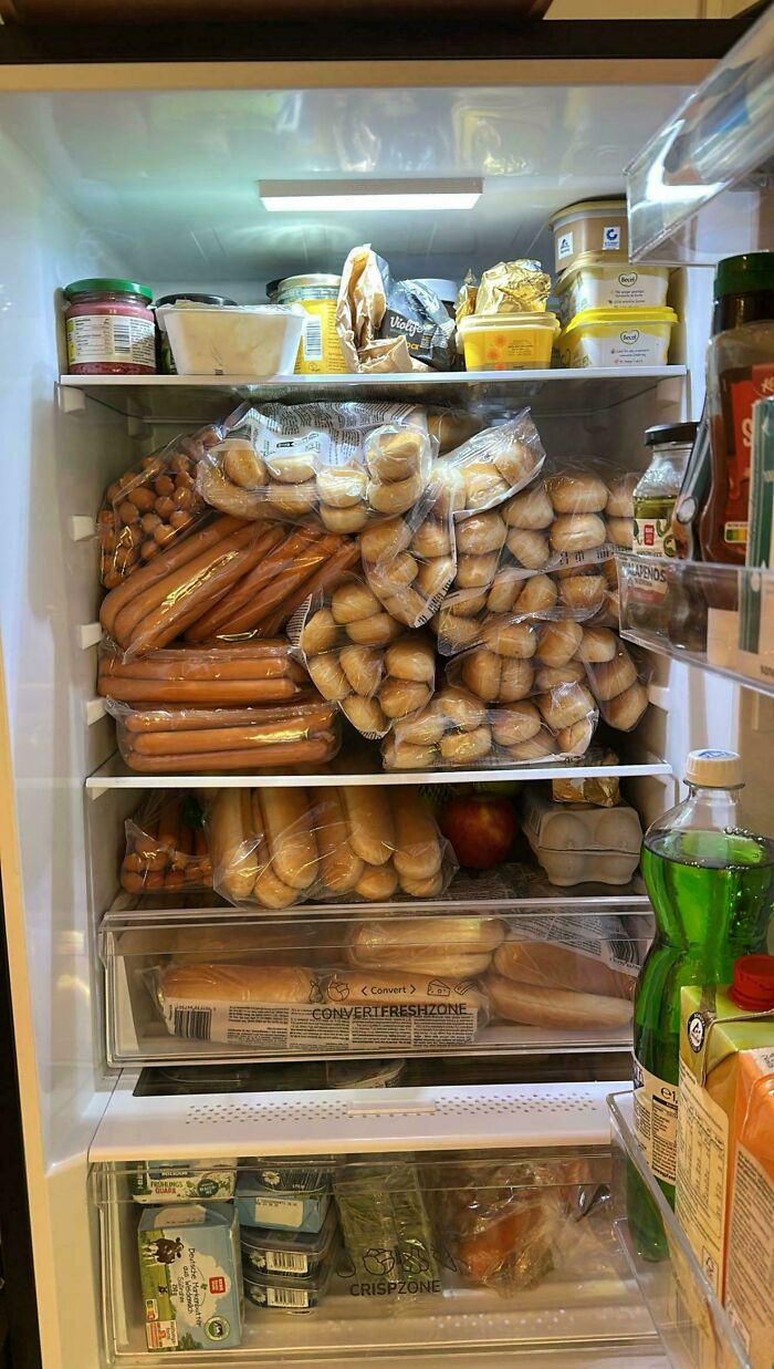 Refrigerator filled with packaged bread, hot dogs, spreads, and various condiments showing interesting fridge contents.