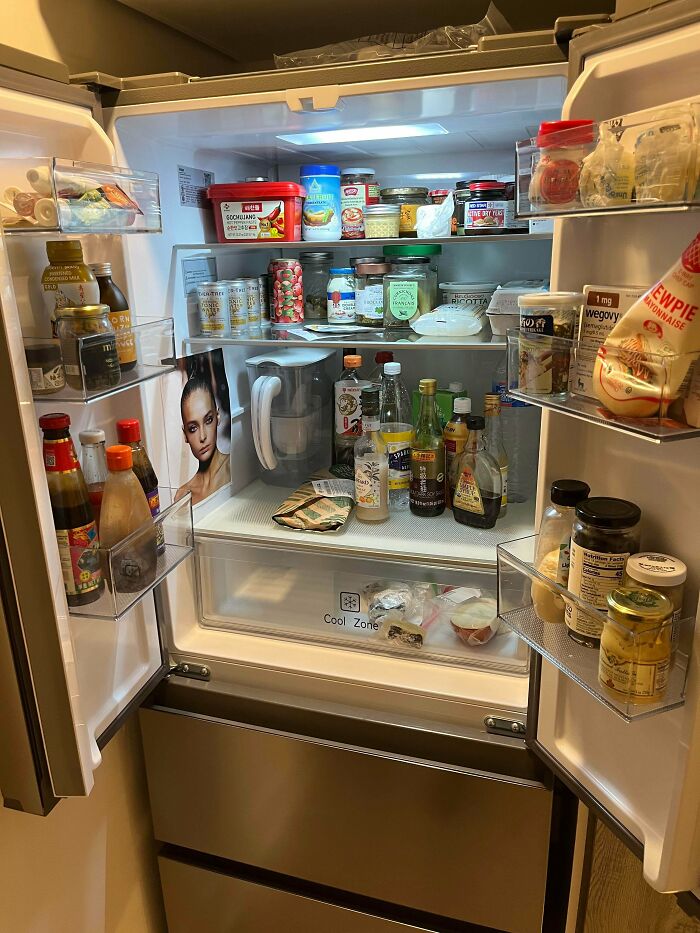 Open fridge filled with various condiments, drinks, and food jars showing interesting fridge contents and organization.