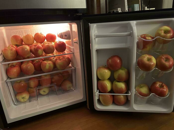 Fridge contents filled entirely with red and yellow apples stacked neatly on shelves and door compartments.