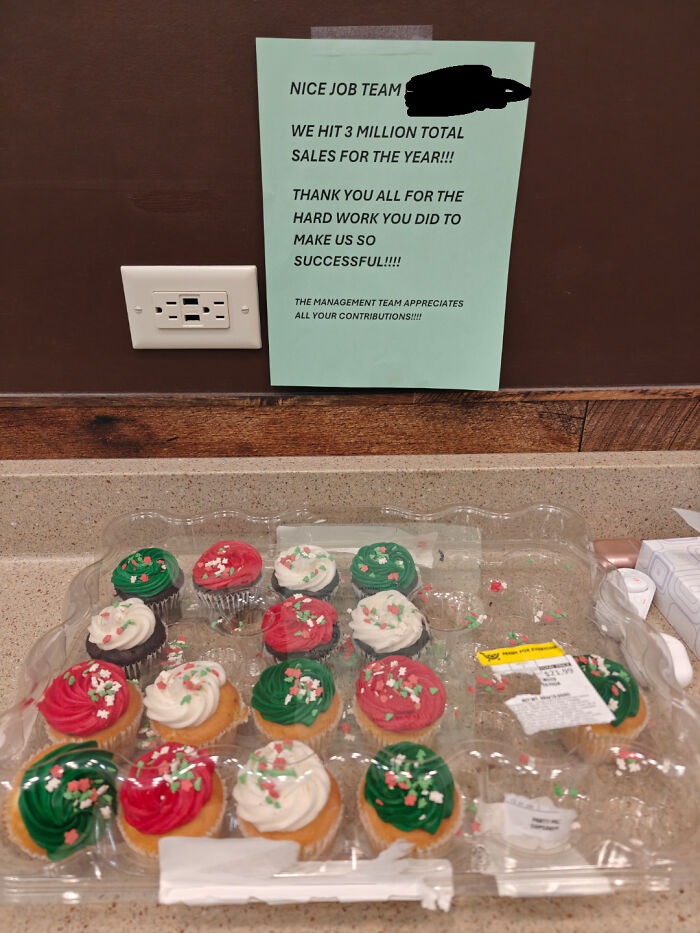 Partially eaten holiday cupcakes in a plastic tray below a team appreciation sign in a workplace setting, U.S. warning images.