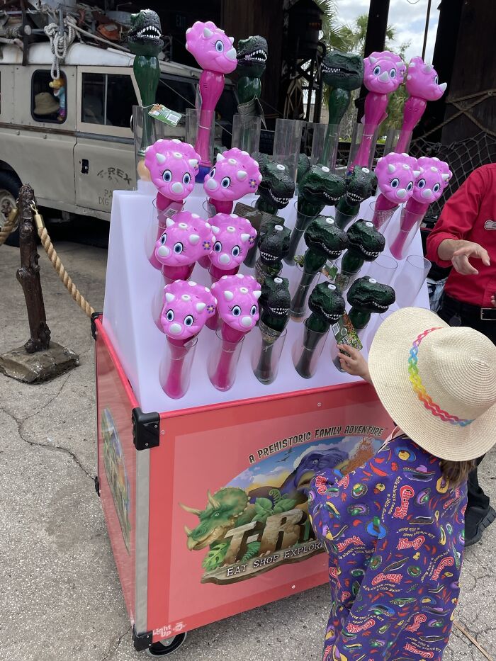 Child choosing between pink and green dinosaur toys, highlighting gendered nonsense in toy marketing.