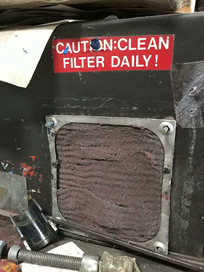 Dirty filter behind a caution sign to clean filter daily showing a reckless work moment in need of safety awareness.