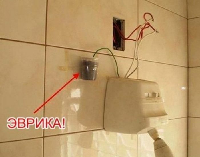 Failed DIY electrical work with wires connected to a plastic cup on tiled wall, illustrating a major DIY fail to be shamed.