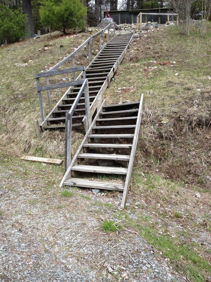 Wooden outdoor stairs with missing steps and unstable handrails showing a clear DIY failure on a hillside.