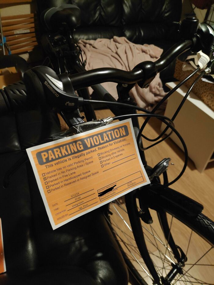 Bicycle inside living room with parking violation ticket, highlighting jerks that made roommates consider living alone.