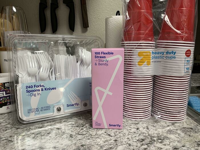 Disposable forks, spoons, knives, heavy duty plastic cups, and flexible straws on a kitchen countertop, messy roommate jerk stuff.