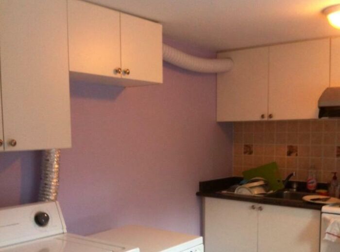 DIY fail showing improperly installed ventilation ducts in a laundry room with cabinets and appliances.