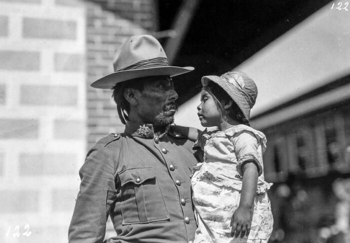 Black and white historical photograph of a man in uniform holding a young girl, depicting a world you'd hardly recognize today.