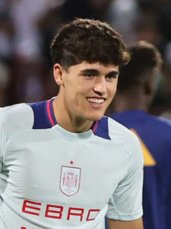 Pau Cubars&iacute; smiling during a football match wearing a white jersey with Spain national team emblem.