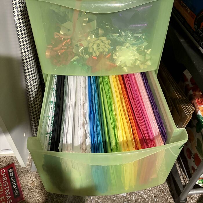 Plastic drawer neatly organized with colorful tissue papers and gift bows arranged by color for order and tidiness.