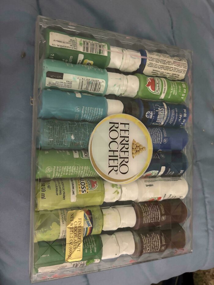 Clear plastic organizer neatly storing paint bottles arranged by color on a blue surface for order and organization.