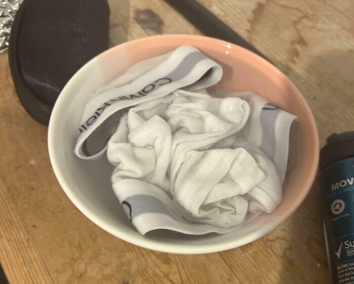 White underwear soaked in a bowl of water on a wooden surface showing roommate annoyance and jerks making others want to live alone.