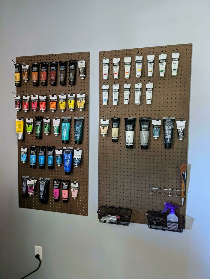 Neatly organized art supplies hanging on pegboards, showcasing a satisfying and orderly arrangement in a creative workspace.