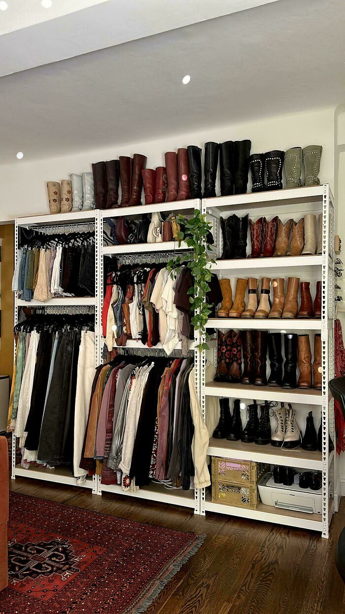 Neatly organized clothing and boots displayed on white shelving units, showcasing a tidy and orderly wardrobe space.
