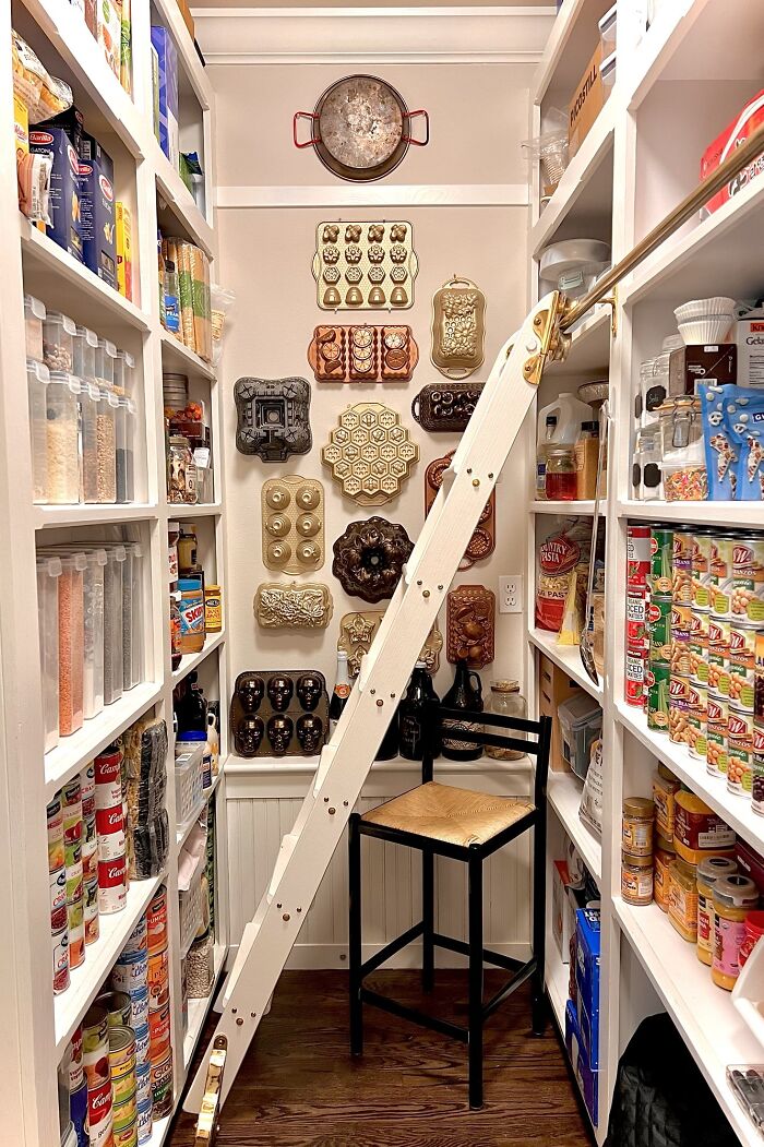 Neatly organized pantry with labeled containers, canned goods, and vintage molds on the wall for satisfying order and storage.