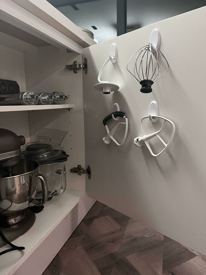 Kitchen mixer attachments neatly organized and hung inside cabinet door for better order and easy access.