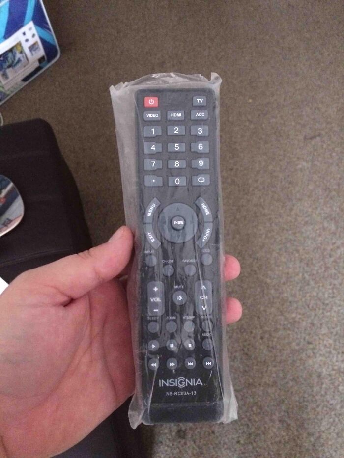 Remote control still wrapped in plastic bag held by a hand, showing a roommate prank from jerks making others want to live alone.