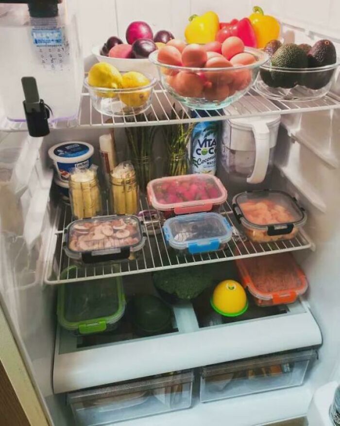 Neatly organized fridge with fruits, veggies, and containers arranged to bring order and satisfy visual appeal.