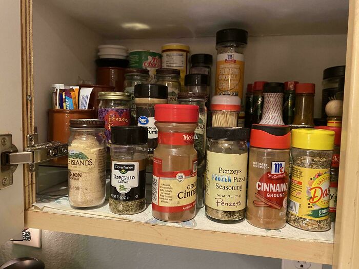 Cluttered spice cabinet with various seasoning jars showing messy roommate habits irritating cohabitants.
