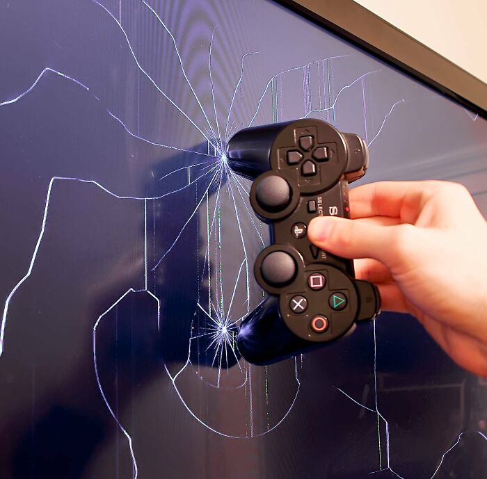 Hand holding a video game controller smashing a c*****d TV screen representing jerks making roommates want to live alone.