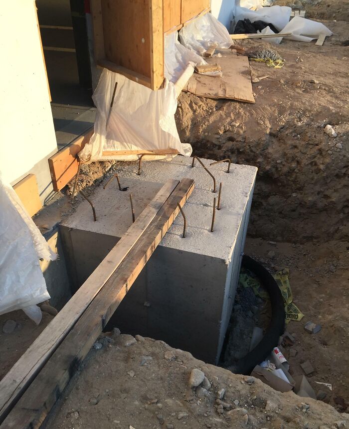 Wooden plank dangerously placed over a deep construction pit showing reckless work moments at a building site.