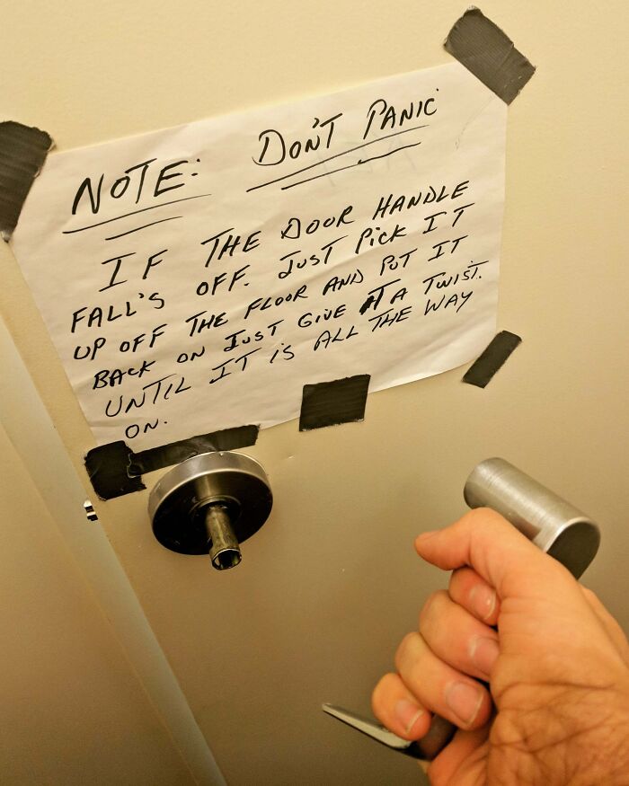 Reckless work moment showing a broken door handle with a handwritten note taped to a door for a risky quick fix.