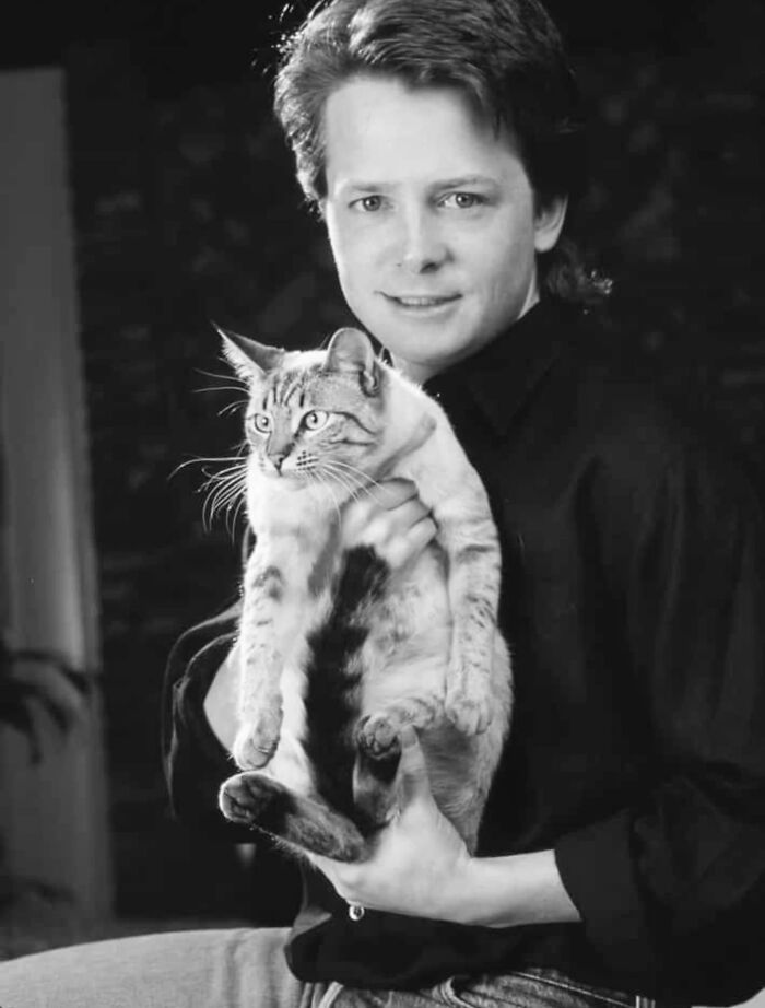 Black and white vintage photo of a person holding a cat, showcasing timeless feline charm and classic cat photography.