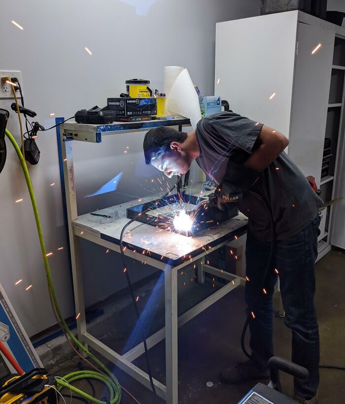 Worker welding metal indoors without proper safety gear, illustrating reckless work moments needing safety awareness.