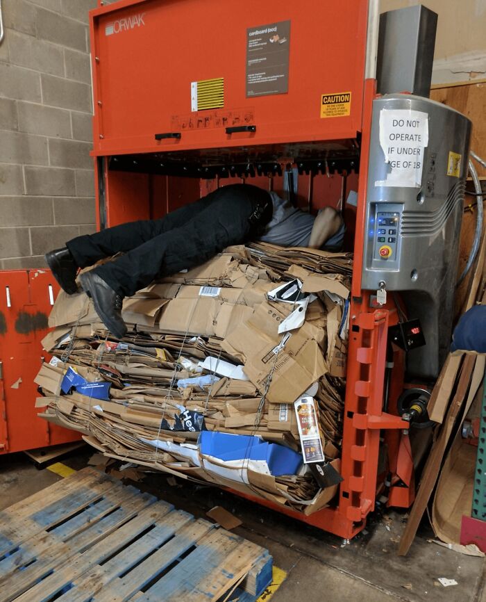 Worker inside cardboard baler in a reckless work moment, highlighting unsafe workplace behavior for safety awareness.