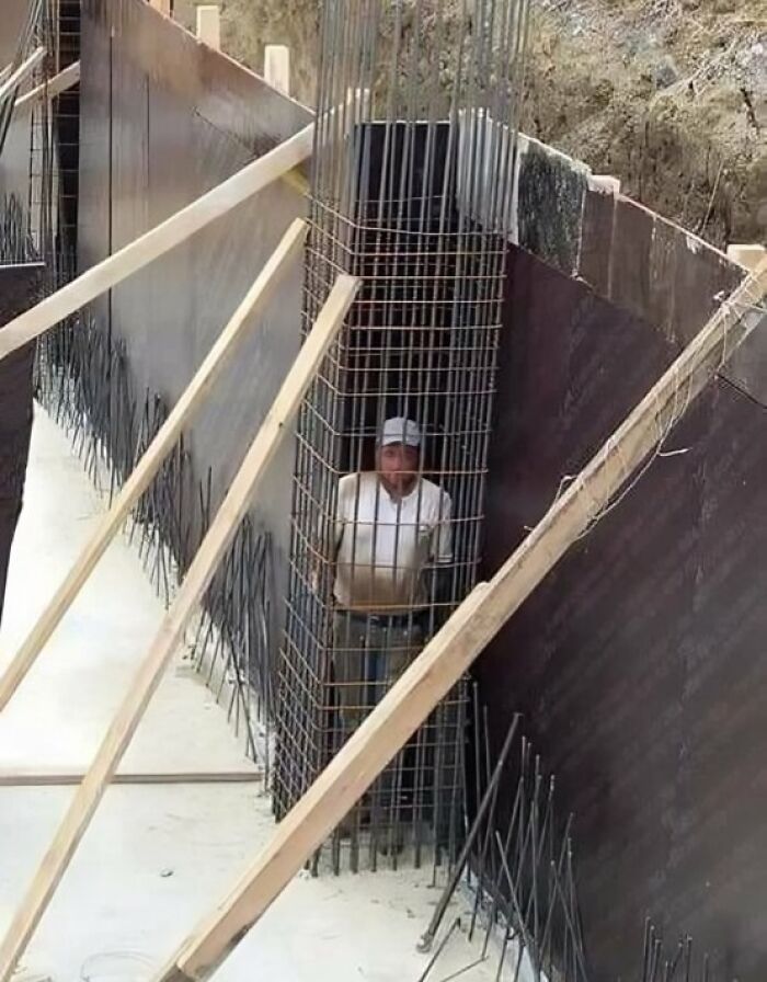 Man trapped inside metal rebar cage at construction site showing reckless work moments without safety precautions.