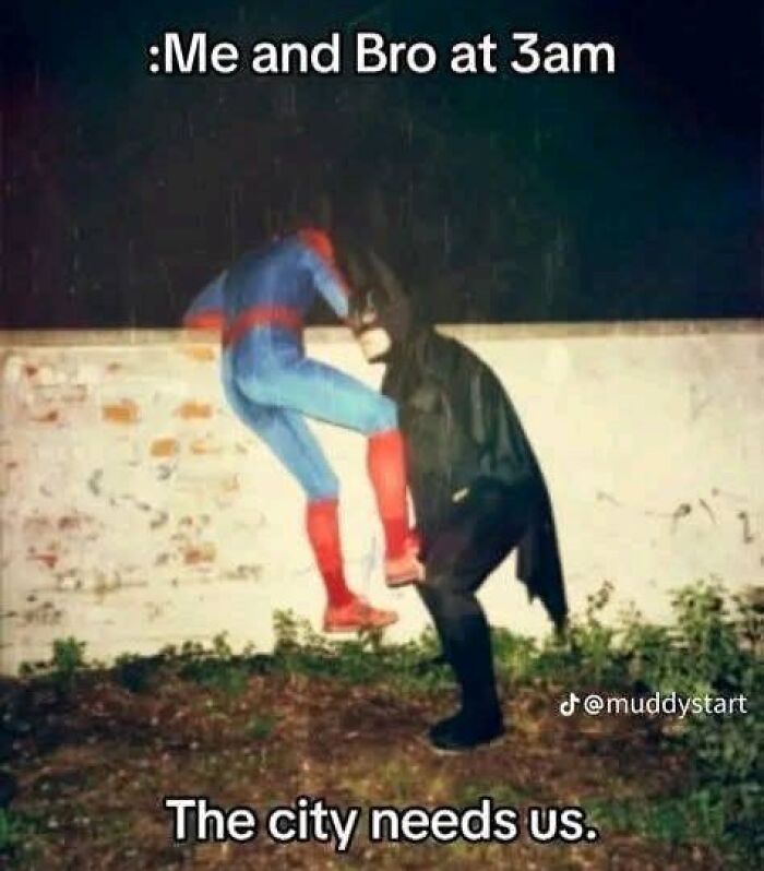 Two people dressed as Spider-Man and Batman at night, humorously posing for funny dad joke posts.