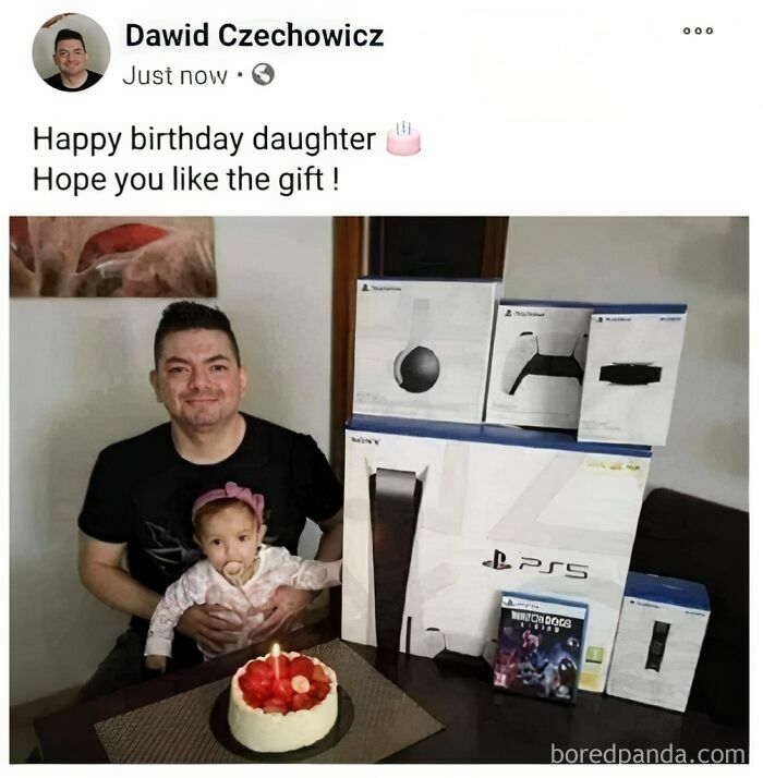 Dad holding baby daughter with a homemade cardboard PS5 and gaming setup as a funny dad joke gift idea.