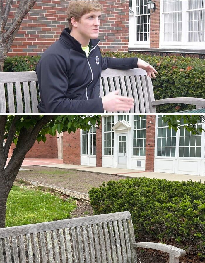 Young man sitting on a wooden bench outdoors, surrounded by bushes and brick buildings, in an unremarkable entertaining photo.