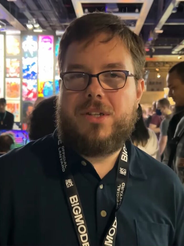 Jason Gastrow wearing glasses and Bigmode lanyard at a busy event, highlighting his bio and career achievements.