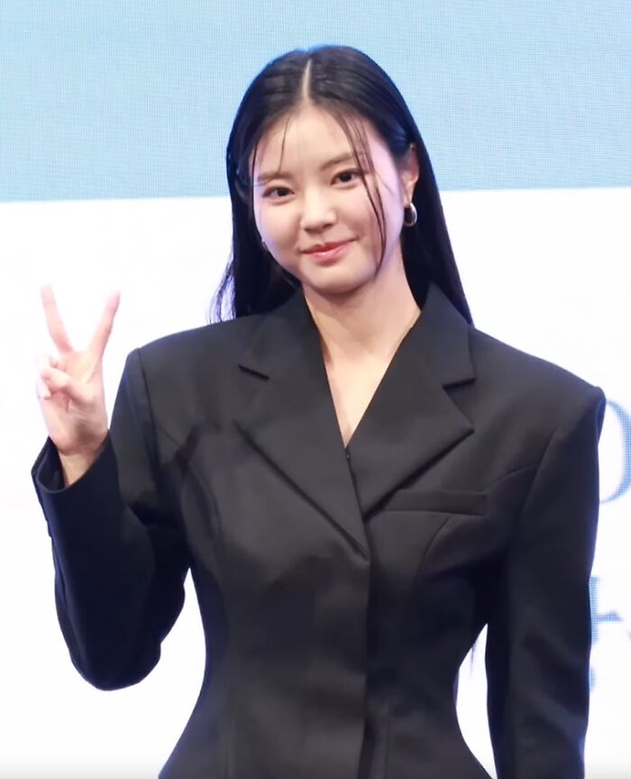 Hong Ye-ji smiling and showing a peace sign, wearing a black blazer at a public event.