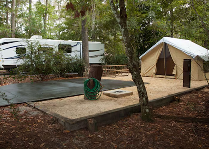 Empty wooded campsite at Disney World with RV, canvas tent, picnic table and coiled hose Empty wooded campsite at Disney World with RV, canvas tent, picnic table and coiled hose