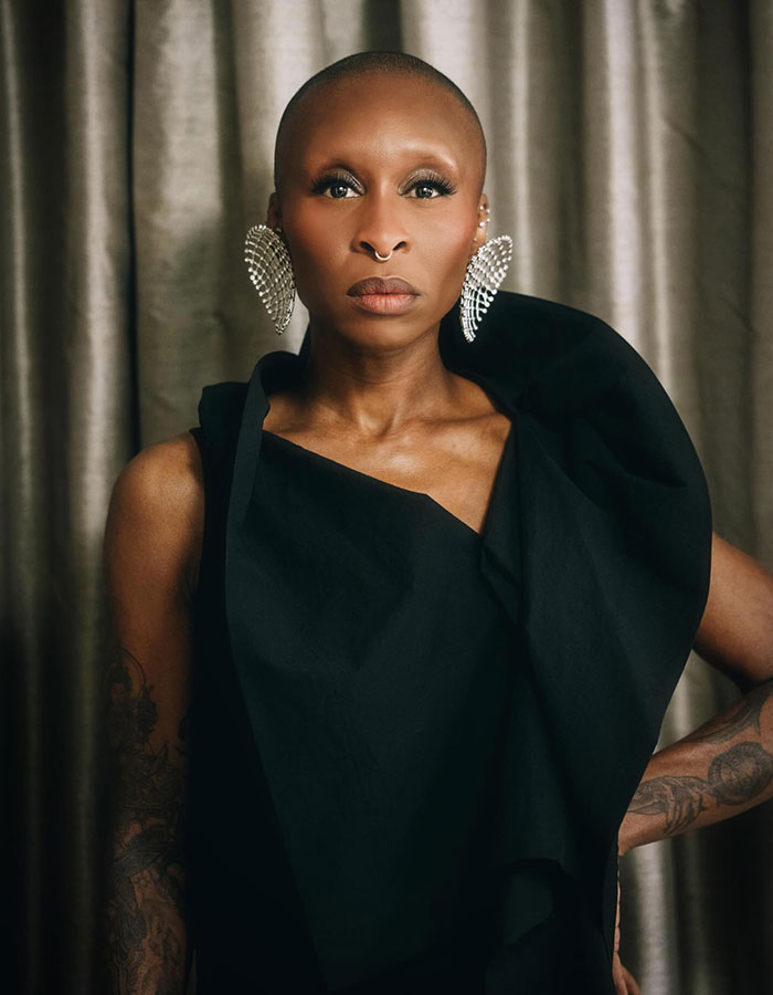 Portrait of a bald woman in a sculpted black gown with dramatic crystal earrings and a poised, confident expression Portrait of a bald woman in a sculpted black gown with dramatic crystal earrings and a poised, confident expression