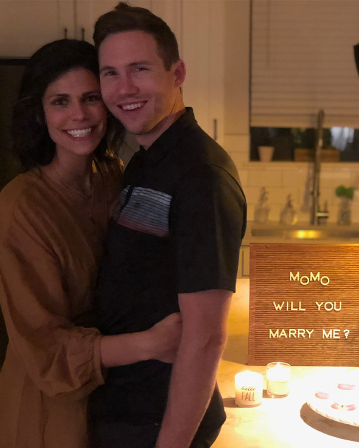 Couple embracing in a kitchen with a marriage proposal sign, unrelated to Ex FBI Agent suggesting motive in Ohio homicide.