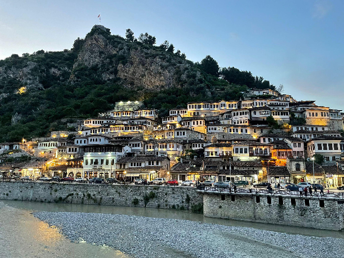 Evening riverside hillside town with lit traditional houses, illustrating Most Stressful Countries travel feature