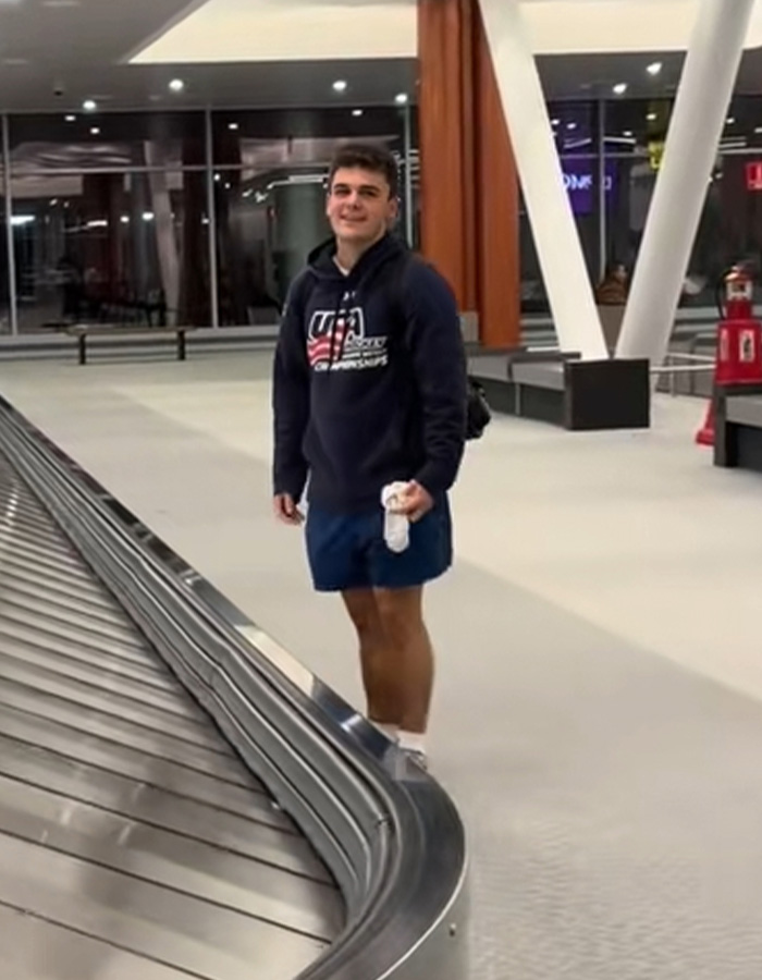 Passenger stands at airport baggage claim holding underwear, viral moment on carousel of shame at luggage area.