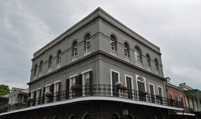 Historic gray building with wrought iron balcony in a town known for being one of the most haunted places in America.