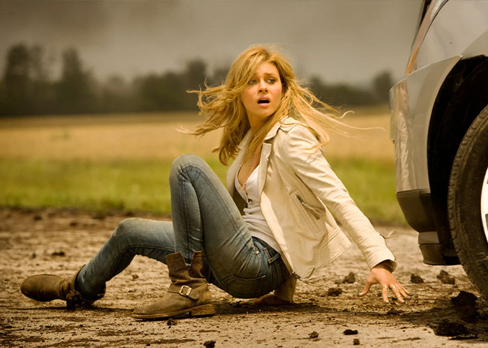 Actress sitting on muddy ground near a car, captured in a tense moment referencing Brooklyn Beckham's scathing rant.
