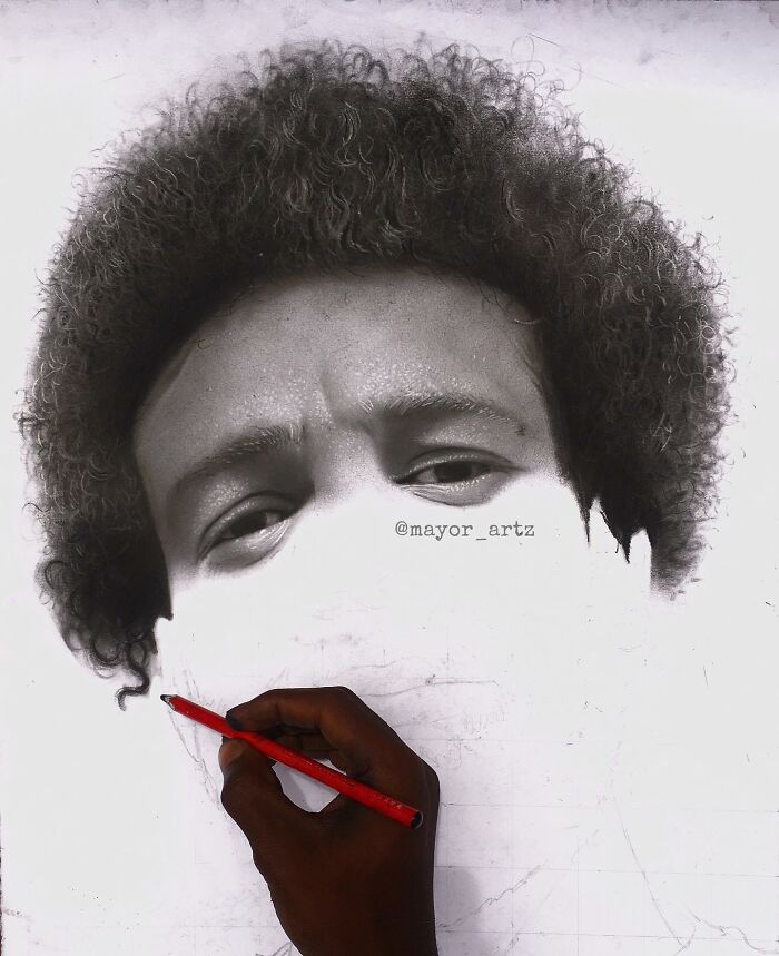 Artist creating a hyperrealistic portrait with a red pencil, showing detailed facial features and curly hair in progress.
